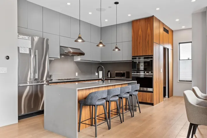 Kitchen featuring appliances with stainless steel finishes, modern cabinets, a sink, ventilation hood, and light wood-style floors