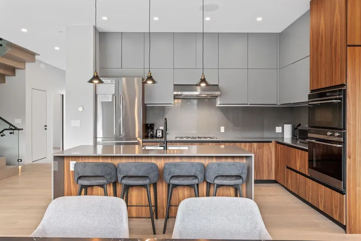 Kitchen featuring stainless steel appliances, modern cabinets, a sink, a breakfast bar area, and decorative backsplash