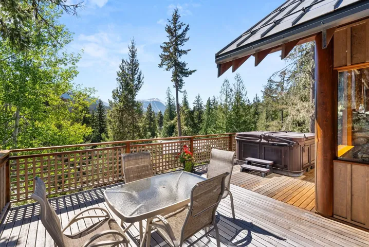 Deck with a hot tub, outdoor dining space, and a mountain view