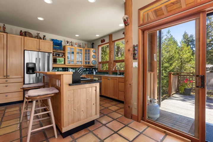 Kitchen featuring glass insert cabinets, a breakfast bar area, light brown cabinetry, recessed lighting, and a center island