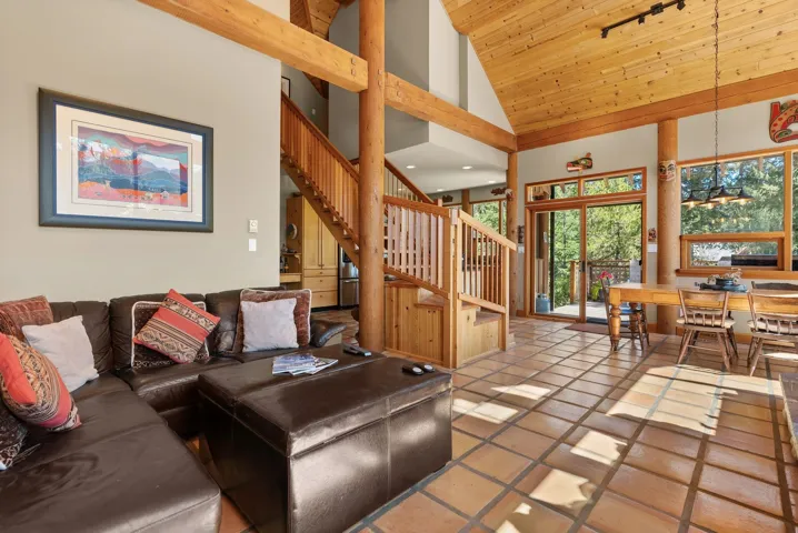 Living area featuring high vaulted ceiling, stairway, light tile patterned floors, and wooden ceiling