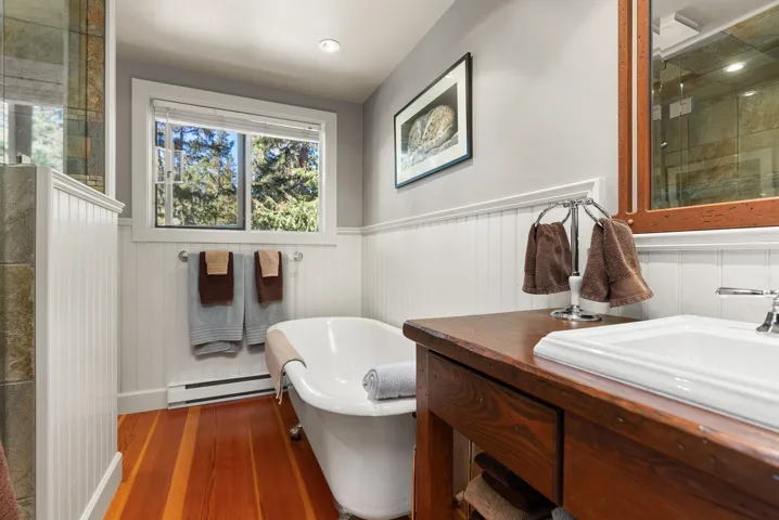 Full bathroom with a shower stall, a soaking tub, wood finished floors, vanity, and a wainscoted wall