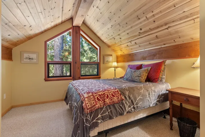 Carpeted bedroom featuring vaulted ceiling and wooden ceiling