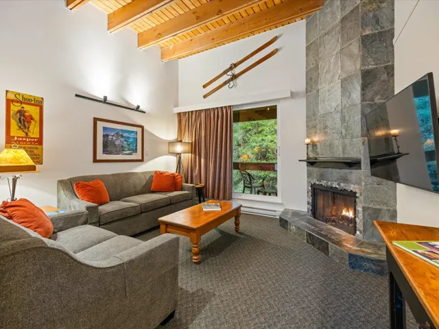 Living area featuring a wooden ceiling with exposed beams, carpet, a tile fireplace, and a high ceiling