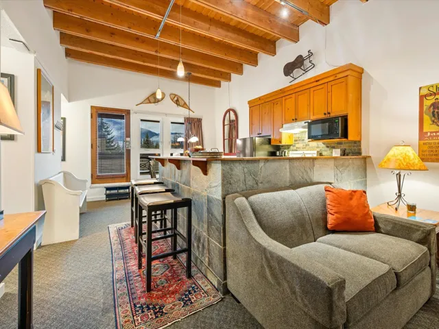 Kitchen featuring hanging light fixtures, dark carpet, tasteful backsplash, a wooden ceiling with exposed beams, and black microwave