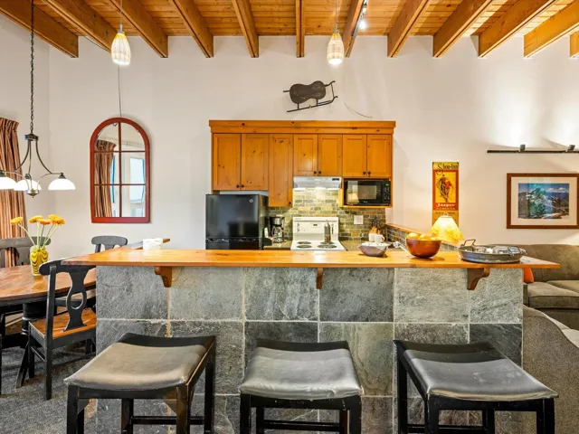 Kitchen with a wooden ceiling with exposed beams, decorative backsplash, a kitchen bar, butcher block counters, and pendant lighting