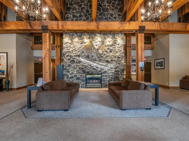 Living room with a chandelier, carpet floors, a fireplace, and beamed ceiling