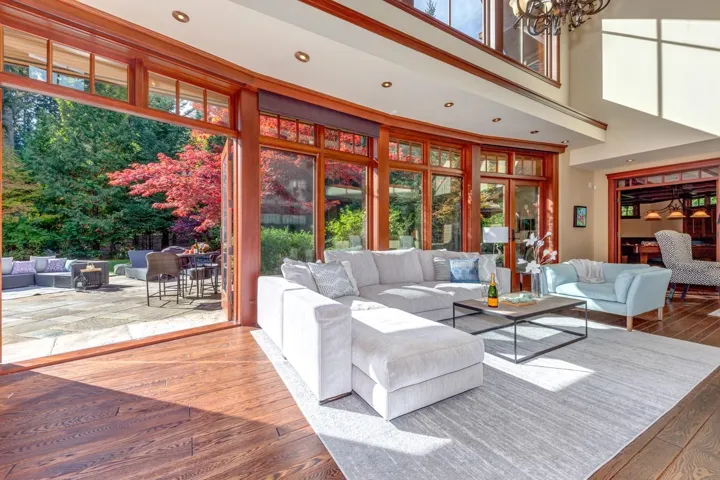 Living room featuring plenty of natural light, wood-type flooring, a high ceiling, recessed lighting, and a chandelier