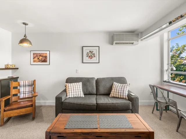 Carpeted living room with a wall mounted mini split and baseboards