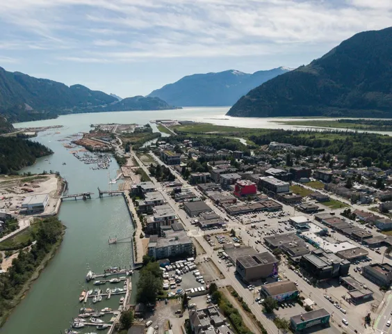 Aerial perspective showcasing a coastal community nestled against a mountainous backdrop