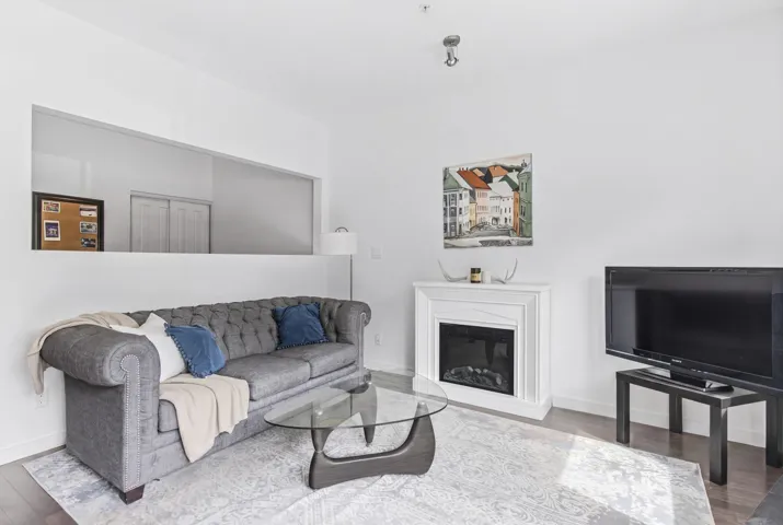 Living area featuring a white electric fireplace, dark wood-finish flooring, and a decorative wall opening