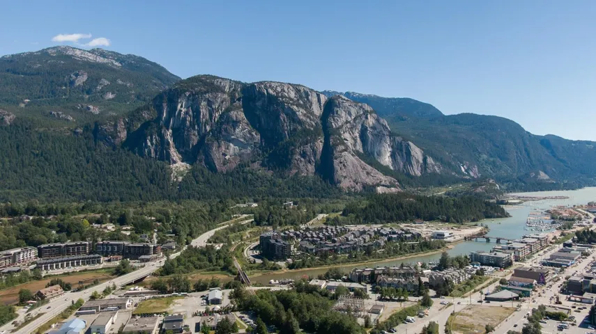 Expansive mountain range backdrop for a waterfront community featuring multi-story residential buildings, a visible marina, and a river