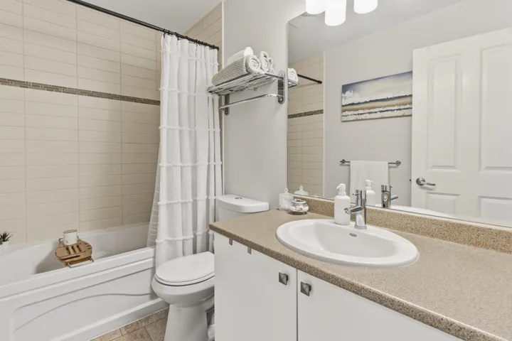 Bathroom featuring a white bathtub, ceramic tile surround with decorative accent band, and a white toilet