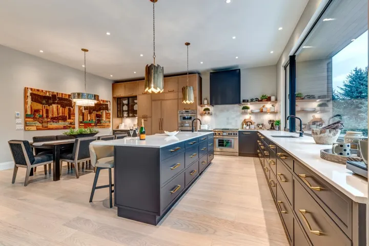 Kitchen featuring a center island with sink, a kitchen breakfast bar, decorative light fixtures, light stone counters, and backsplash