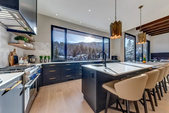Kitchen featuring high end stove, pendant lighting, exhaust hood, light wood-style floors, and a kitchen island with sink