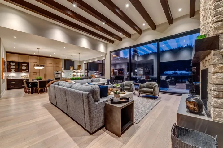 Living room with beam ceiling, light wood-type flooring, a stone fireplace, and recessed lighting