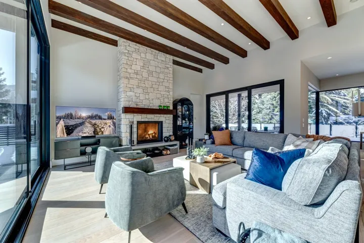 Living area featuring beamed ceiling, wood finished floors, a fireplace, and a towering ceiling