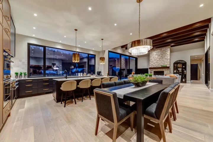 Dining area featuring a stone fireplace, light wood-style flooring, beam ceiling, and recessed lighting
