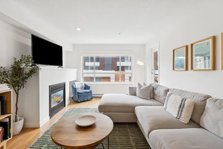 Living room with wood finished floors, a glass covered fireplace, a textured ceiling, recessed lighting, and a baseboard heating unit