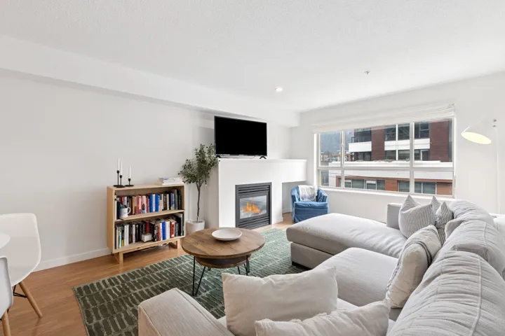 Living room with a glass covered fireplace, wood finished floors, and recessed lighting