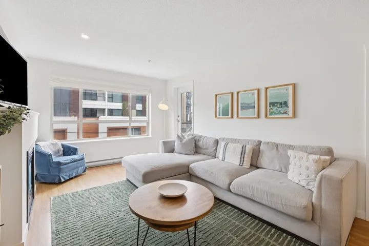 Living room with wood finished floors, a baseboard radiator, a textured ceiling, and recessed lighting