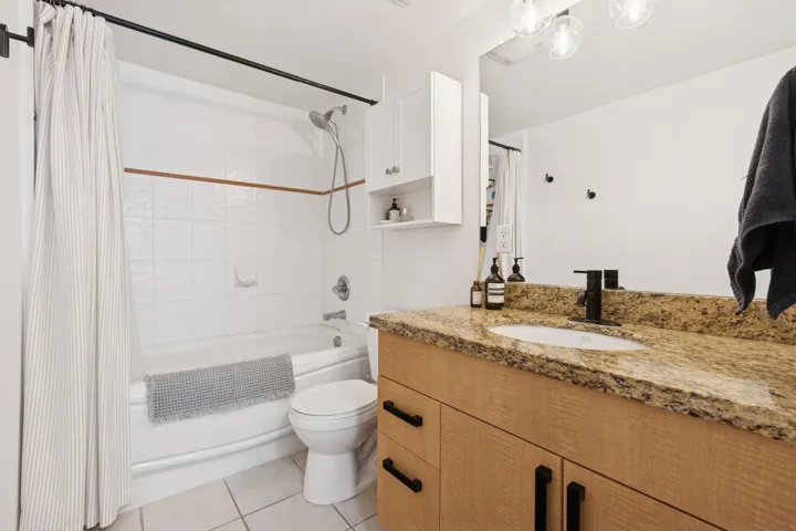 Bathroom featuring shower / tub combo, vanity, and light tile patterned flooring