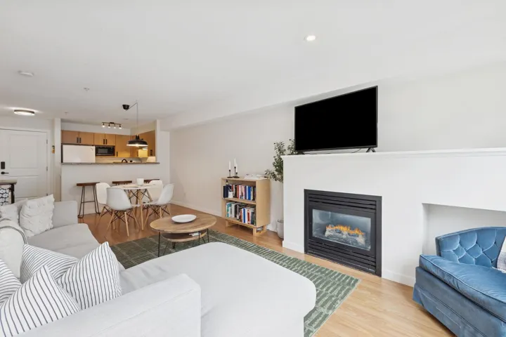 Living area with light wood-style flooring and a glass covered fireplace