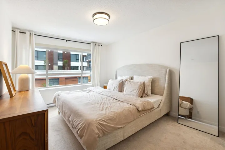 Carpeted bedroom featuring a textured ceiling and a baseboard heating unit