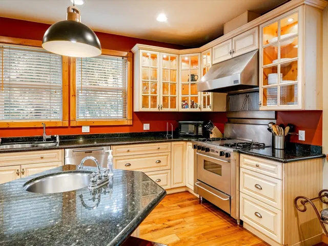 Kitchen with light wood-style floors, under cabinet range hood, a sink, and stainless steel appliances