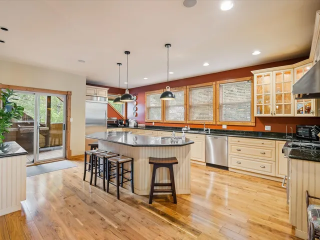 Kitchen with a breakfast bar, appliances with stainless steel finishes, a center island, light wood-style flooring, and recessed lighting