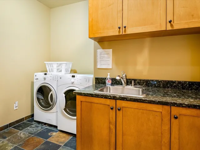Laundry area with independent washer and dryer, baseboards, a sink, cabinet space, and stone finish flooring