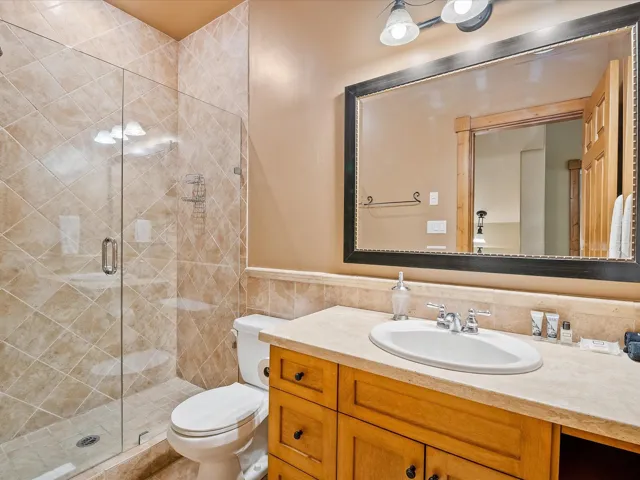 Full bathroom with tile walls, vanity, toilet, and a shower stall