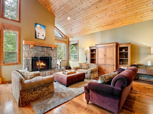 Living room featuring a fireplace, high vaulted ceiling, hardwood flooring