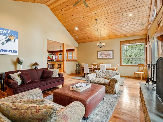 Living area with high vaulted ceiling, a chandelier, baseboards, light wood-type flooring, and wooden ceiling