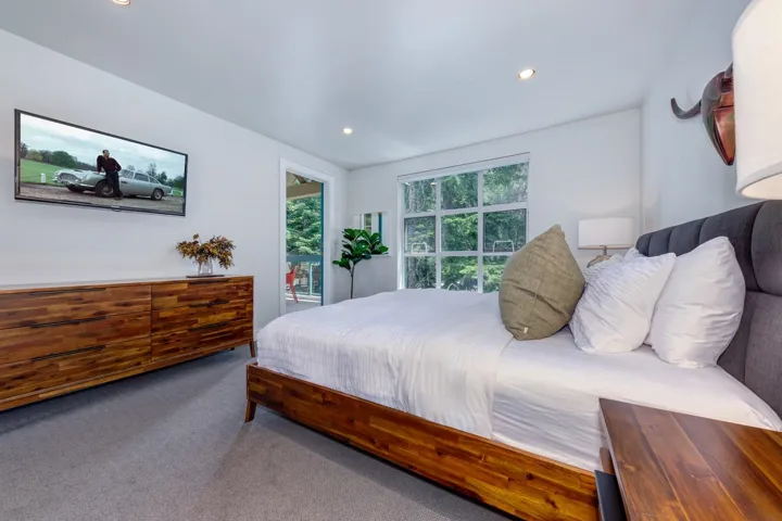 Carpeted bedroom featuring a wall-mounted television, recessed lighting, and a window with exterior views