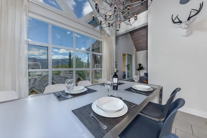 Formal dining area with large pane windows, vaulted wood-finish ceiling, and a contemporary chandelier