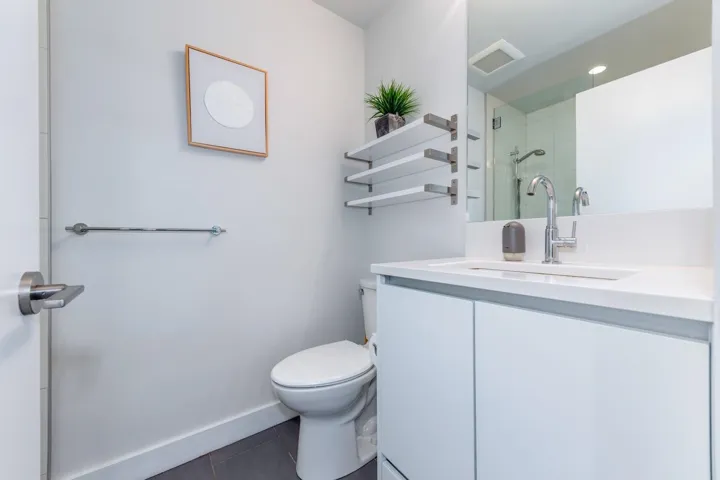 Contemporary bathroom featuring a white vanity with integrated sink, chrome faucet, and mirrored medicine cabinet
