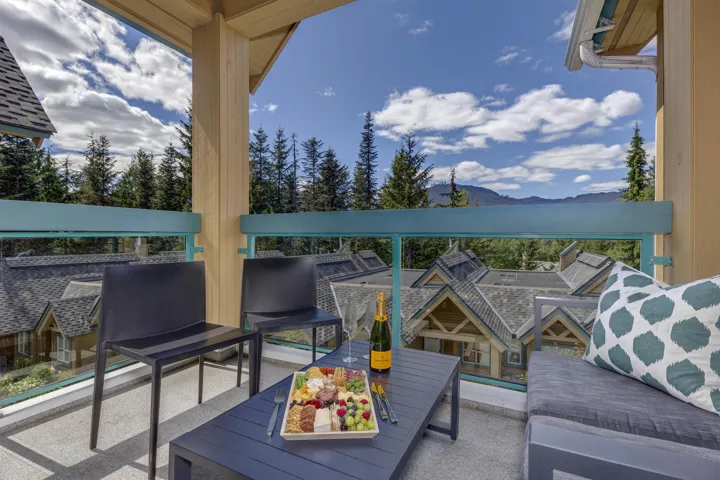 Outdoor balcony featuring glass railings, a teal top rail, and a wood support column