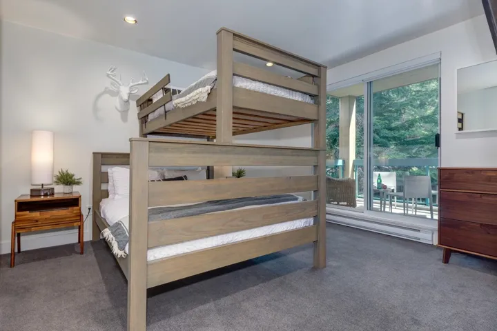 Room featuring bunk beds with a light wood finish, recessed ceiling lighting, and a sliding glass door providing access to an outdoor patio area