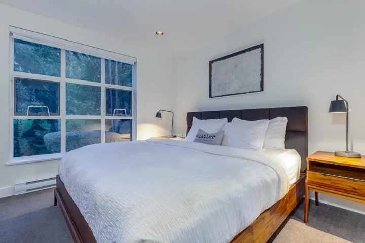Window wall with multiple panes, recessed ceiling lighting, upholstered headboard, and wood-finish flooring