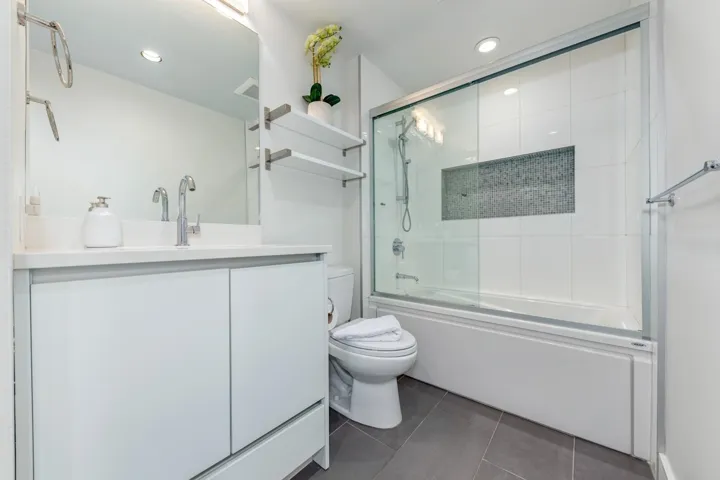 Contemporary bathroom featuring a white vanity with integrated sink, chrome faucet, and overhead bar lighting