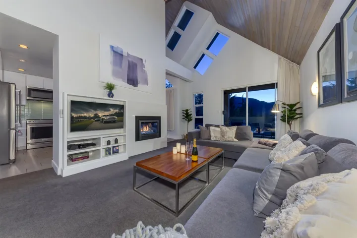 Living area featuring a vaulted wood-finish ceiling, multiple skylights, and a built-in fireplace