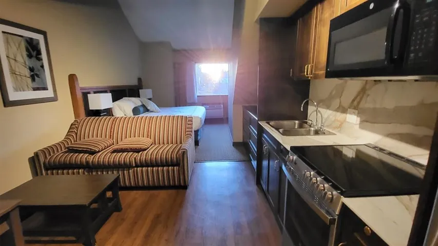 Kitchen with a sink, dark wood finished floors, stainless steel electric range oven, black microwave, and light countertops