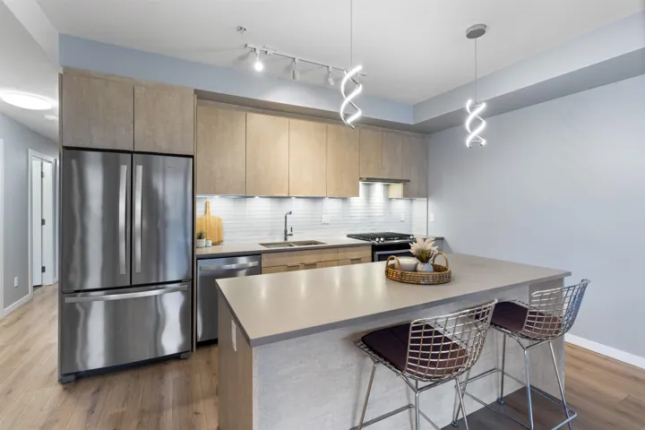 Kitchen with appliances with stainless steel finishes, dark wood-style floors, backsplash, hanging light fixtures, and modern cabinets