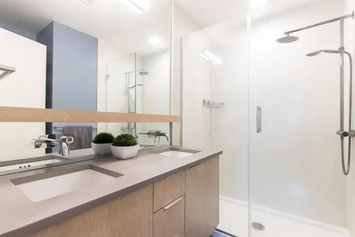 Full bath featuring double vanity and a stall shower
