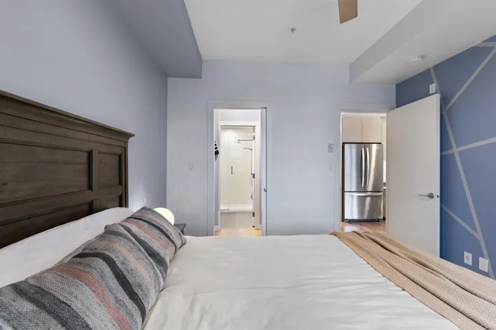 Bedroom featuring freestanding refrigerator, ceiling fan, and connected bathroom
