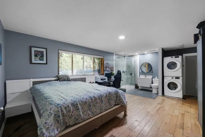 Bedroom featuring light wood-style floors, stacked washer and clothes dryer, recessed lighting, connected bathroom, and a desk