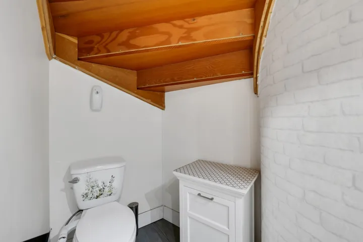 Half bath featuring brick wall and toilet