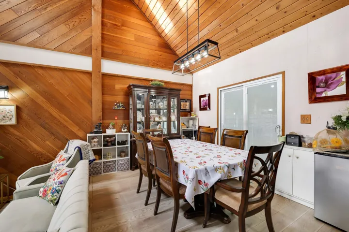 Dining area featuring wooden walls, a vaulted wooden ceiling, and light wood-style flooring