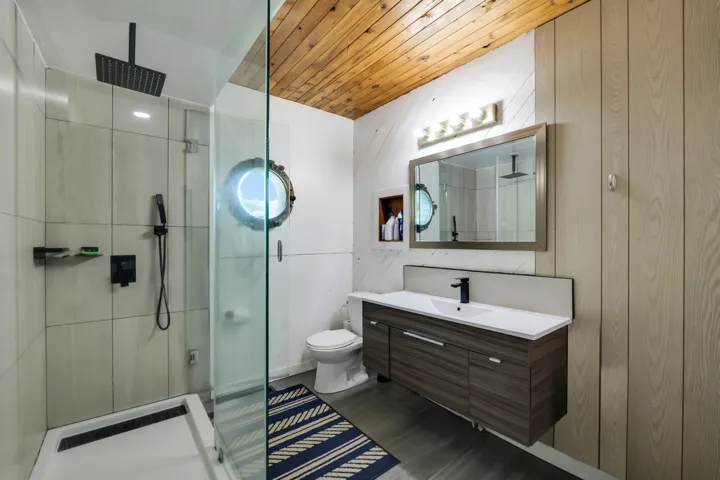 Full bath featuring vanity, a stall shower, wooden ceiling, and wood walls